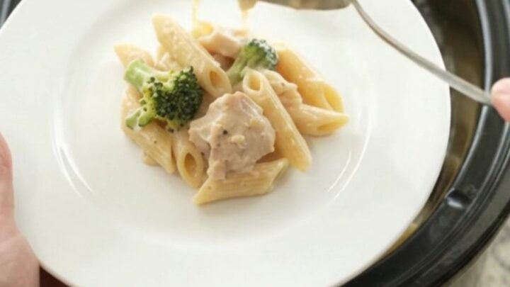 Creamy Crockpot Chicken Alfredo Penne with melted cheese and broccoli in a slow cooker