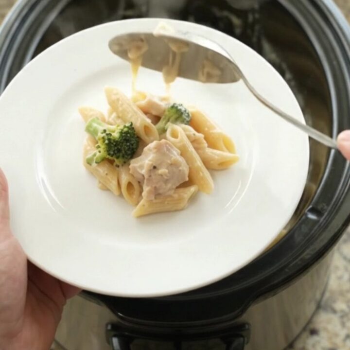 Creamy Crockpot Chicken Alfredo Penne with melted cheese and broccoli in a slow cooker
