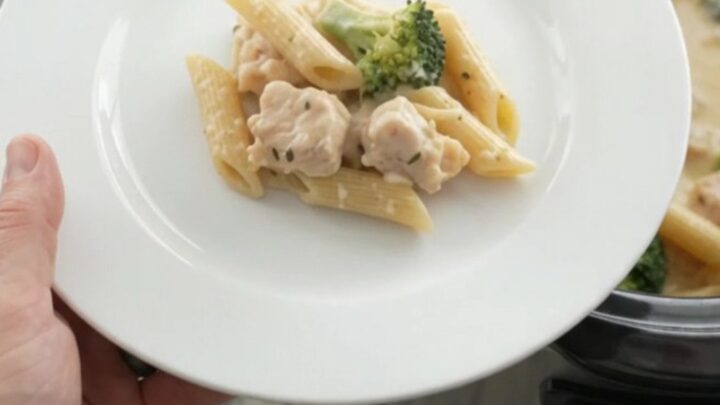 Slow cooker filled with creamy chicken Alfredo penne, topped with melted provolone and ricotta.
