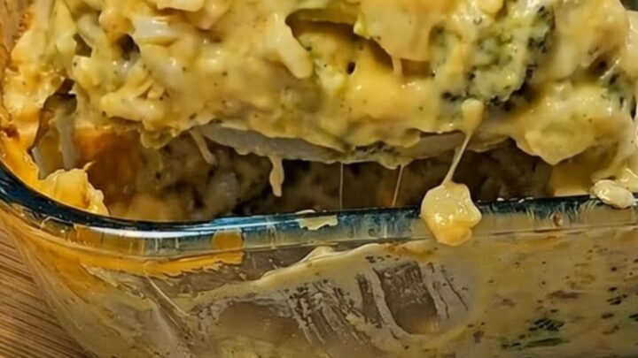 A large serving spoon lifting a creamy, piping-hot scoop of broccoli cheese casserole with melted cheese stretching downward