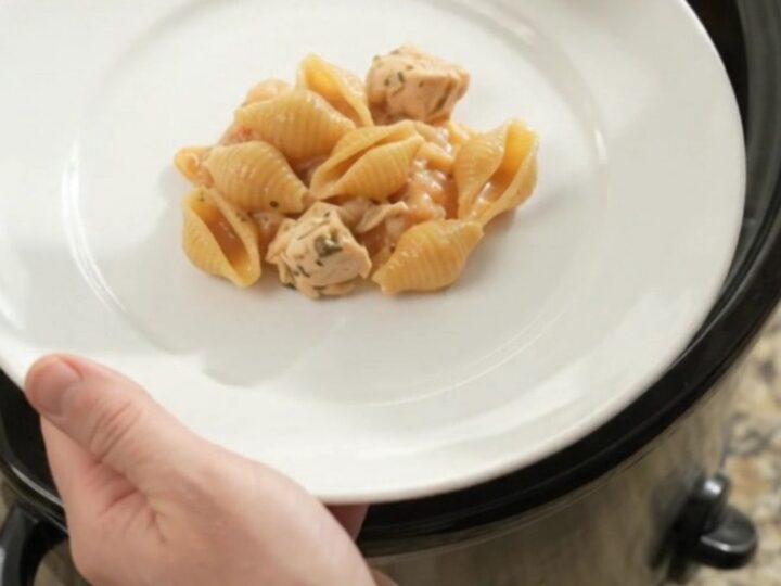 Slow cooker filled with creamy Boursin chicken red pepper shells pasta, topped with melted fontina and steam rising.