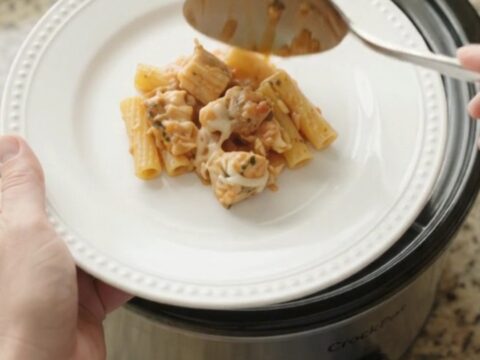 Slow cooker filled with creamy chicken baked ziti, topped with melted mozzarella and fresh herbs.