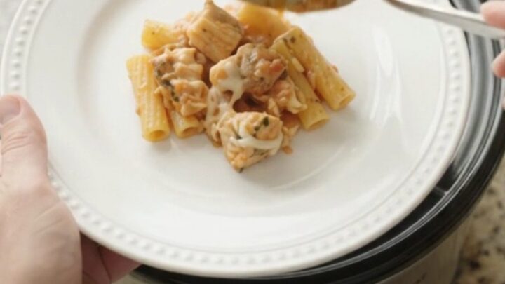 Slow cooker filled with creamy chicken baked ziti, topped with melted mozzarella and fresh herbs.