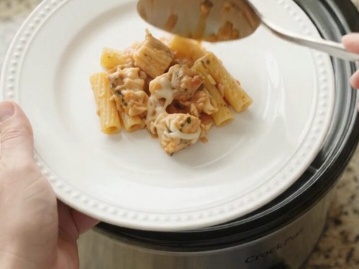 Slow cooker filled with creamy chicken baked ziti, topped with melted mozzarella and fresh herbs.