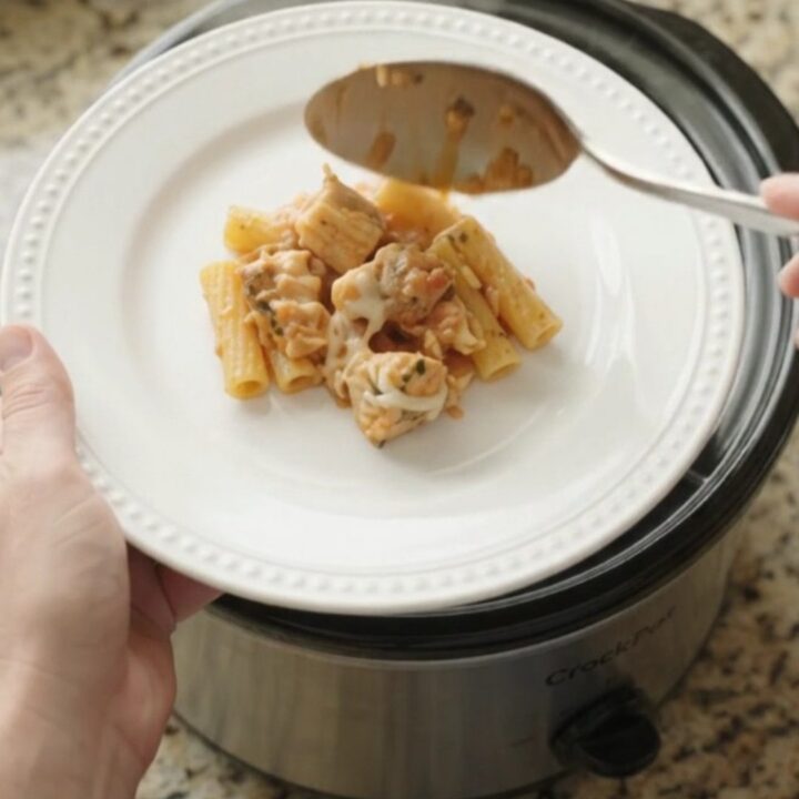 Slow cooker filled with creamy chicken baked ziti, topped with melted mozzarella and fresh herbs.