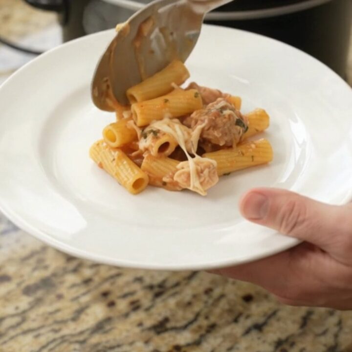 Slow cooker filled with bubbling Parmesan chicken baked ziti, topped with melted cheese and golden crust.