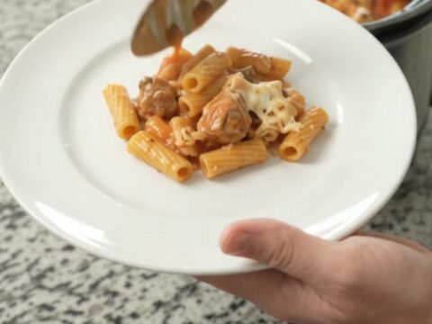 Crockpot Chicken Baked Ziti with bubbling cheese and marinara sauce in a black slow cooker