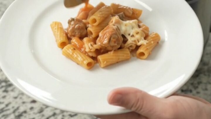 Crockpot Chicken Baked Ziti with bubbling cheese and marinara sauce in a black slow cooker