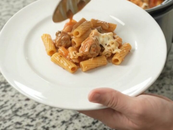 Crockpot Chicken Baked Ziti with bubbling cheese and marinara sauce in a black slow cooker