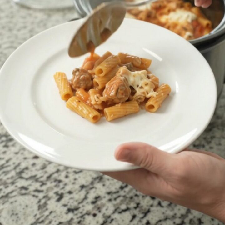 Crockpot Chicken Baked Ziti with bubbling cheese and marinara sauce in a black slow cooker