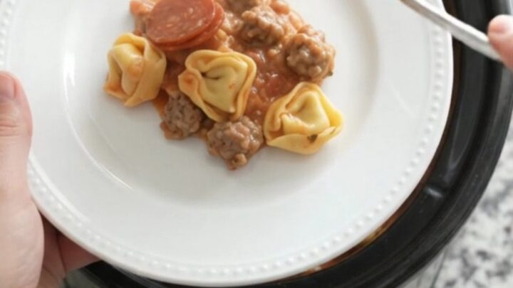 Slow cooker filled with creamy tortellini, pepperoni, sausage, and melted cheese