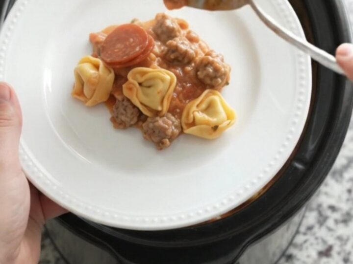 Slow cooker filled with creamy tortellini, pepperoni, sausage, and melted cheese