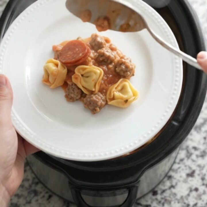 Slow cooker filled with creamy tortellini, pepperoni, sausage, and melted cheese