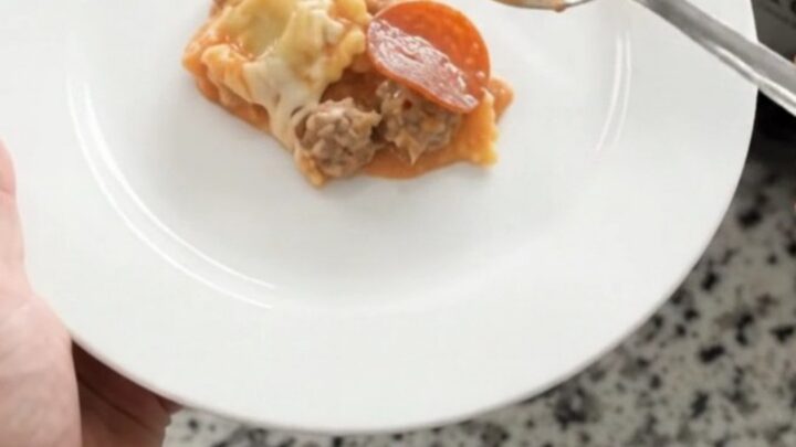 Slow cooker filled with bubbling vodka ravioli, topped with melted mozzarella and pepperoni