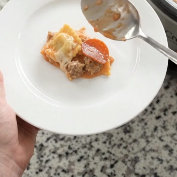 Slow cooker filled with bubbling vodka ravioli, topped with melted mozzarella and pepperoni