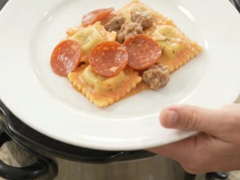 Bubbling Crockpot ravioli bake with pepperoni, sausage, and melted cheese.