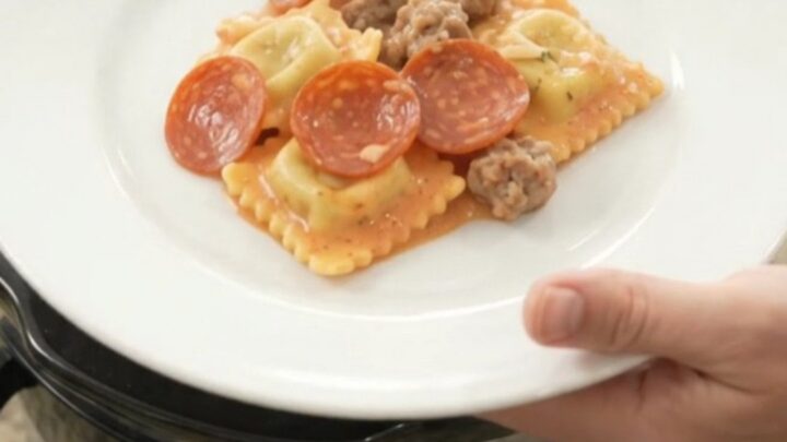 Bubbling Crockpot ravioli bake with pepperoni, sausage, and melted cheese.