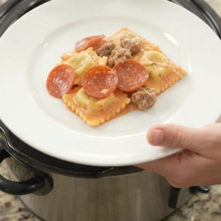 Bubbling Crockpot ravioli bake with pepperoni, sausage, and melted cheese.