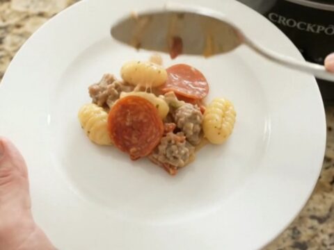 A bubbling Crockpot filled with creamy Boursin pepperoni sausage gnocchi, topped with melted fontina and steam rising.