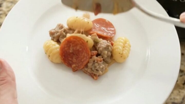 A bubbling Crockpot filled with creamy Boursin pepperoni sausage gnocchi, topped with melted fontina and steam rising.