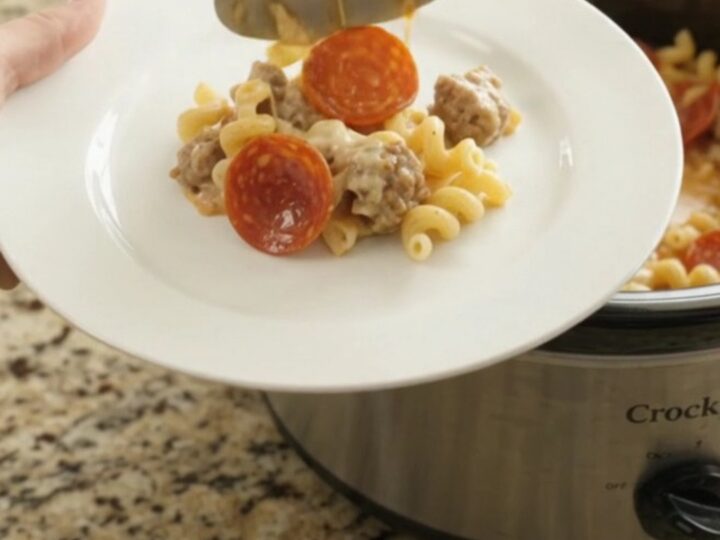 A creamy slow cooker cavatappi with pepperoni and sausage, topped with melted cheese and Parmesan.