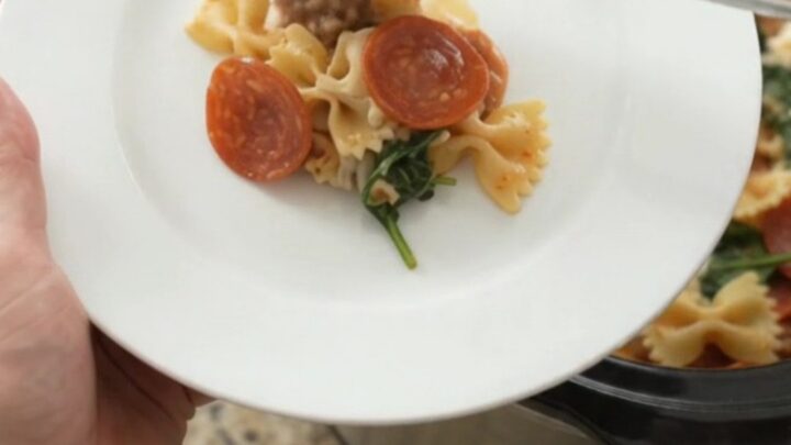Slow cooker filled with bubbling pepperoni sausage pesto farfalle