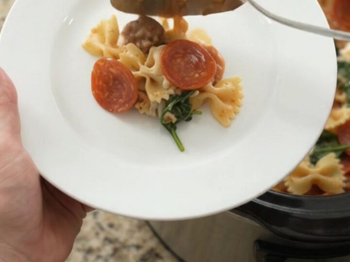 Slow cooker filled with bubbling pepperoni sausage pesto farfalle