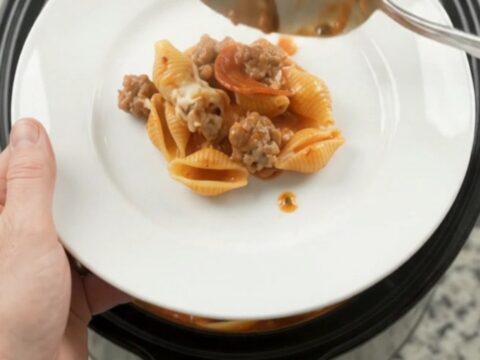 Slow cooker pasta with pepperoni, sausage, and melted mozzarella in a black crockpot