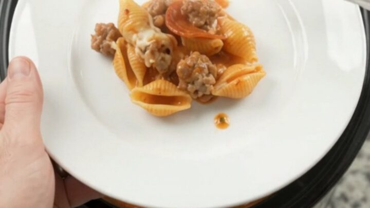 Slow cooker pasta with pepperoni, sausage, and melted mozzarella in a black crockpot