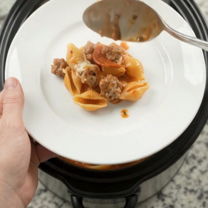 Slow cooker pasta with pepperoni, sausage, and melted mozzarella in a black crockpot