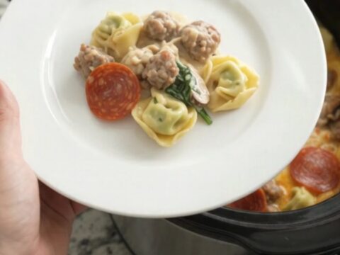 Bubbling slow-cooker tortellini with melted cheese and pepperoni in a black Crockpot