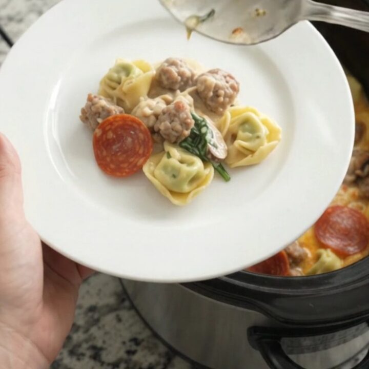 Bubbling slow-cooker tortellini with melted cheese and pepperoni in a black Crockpot