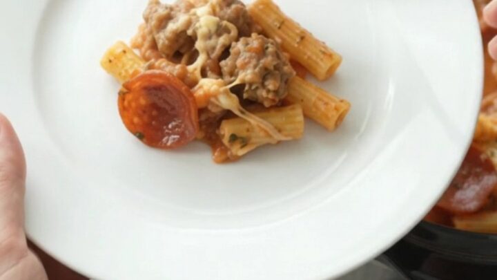 Slow cooker filled with bubbling baked ziti topped with melted provolone and ricotta