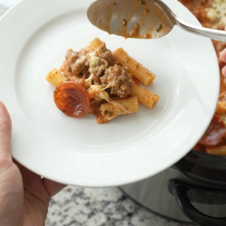 Slow cooker filled with bubbling baked ziti topped with melted provolone and ricotta