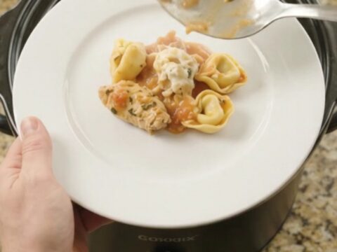 A bubbling Crockpot full of creamy chicken tortellini with melted provolone and ricotta.