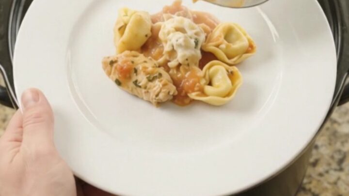 A bubbling Crockpot full of creamy chicken tortellini with melted provolone and ricotta.