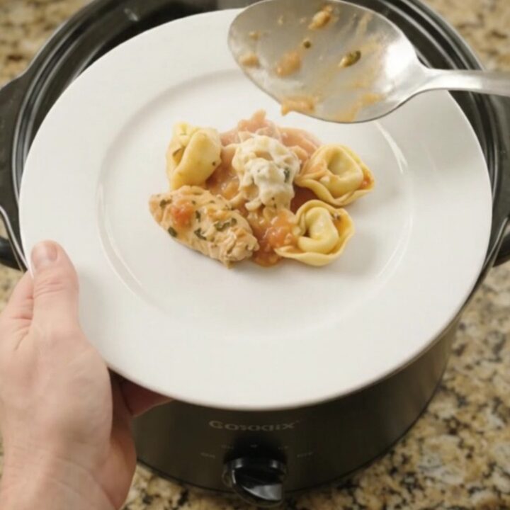 A bubbling Crockpot full of creamy chicken tortellini with melted provolone and ricotta.