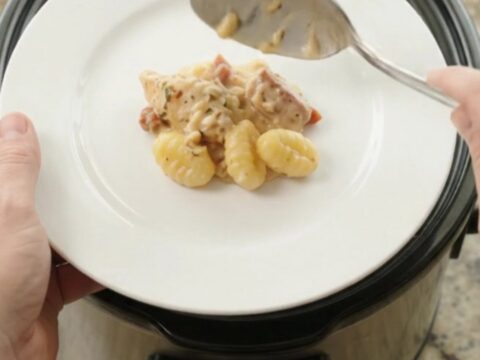 Creamy Crockpot chicken Tuscan gnocchi in a slow cooker, topped with melted provolone and ricotta