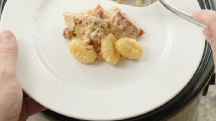 Creamy Crockpot chicken Tuscan gnocchi in a slow cooker, topped with melted provolone and ricotta