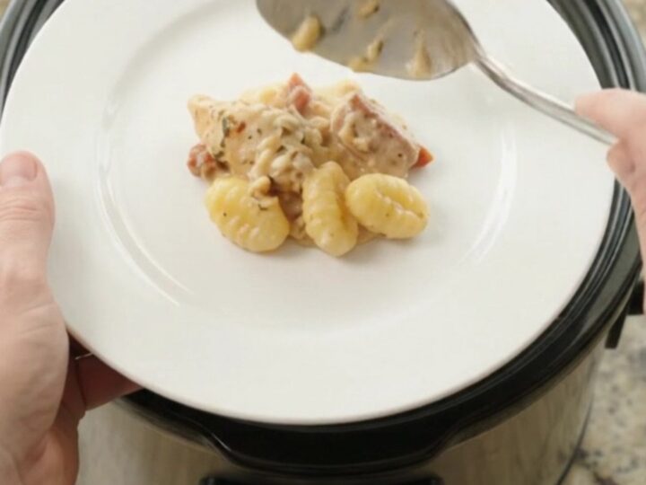 Creamy Crockpot chicken Tuscan gnocchi in a slow cooker, topped with melted provolone and ricotta