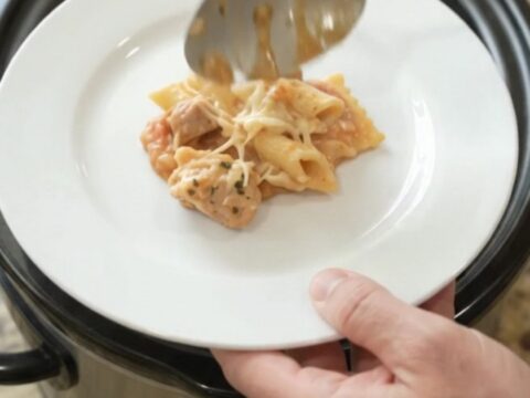 Slow cooker filled with cheesy chicken vodka ravioli, topped with melted Italian cheeses and Parmesan.
