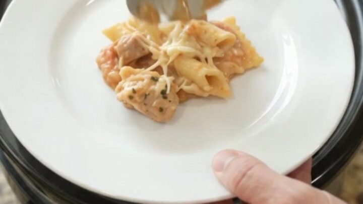Slow cooker filled with cheesy chicken vodka ravioli, topped with melted Italian cheeses and Parmesan.