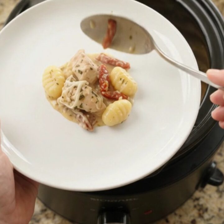 Creamy slow cooker chicken gnocchi with melted Boursin and fontina, bubbling in a black Crockpot