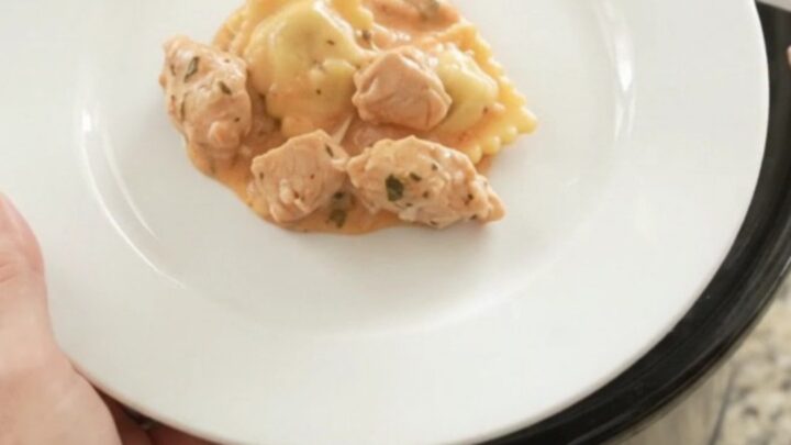 Crockpot Boursin Chicken Vodka Ravioli in a black slow cooker with melted cheese and sauce.