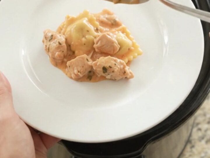Crockpot Boursin Chicken Vodka Ravioli in a black slow cooker with melted cheese and sauce.