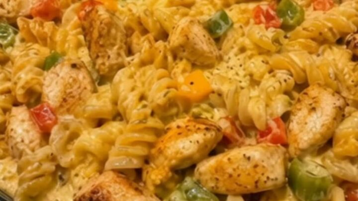 A close-up shot of a large skillet filled with creamy Rotel chicken pasta, garnished with peppers and seared chicken pieces.