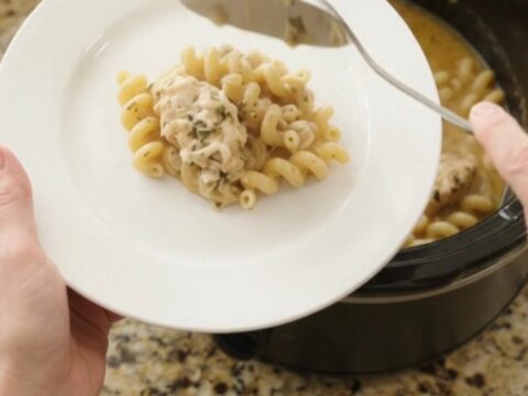 Slow cooker filled with creamy chicken cavatappi, topped with melted provolone and ricotta.