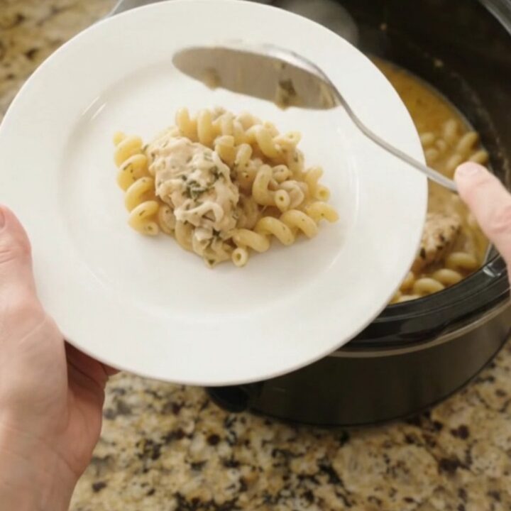 Slow cooker filled with creamy chicken cavatappi, topped with melted provolone and ricotta.