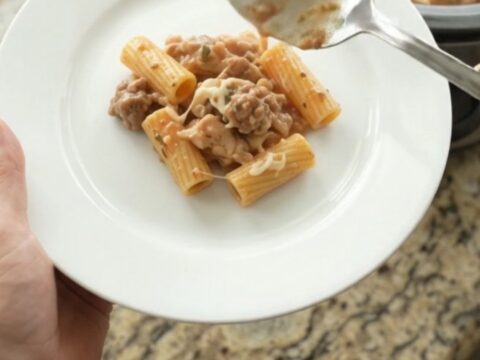 Creamy Boursin chicken rigatoni in a black slow cooker, topped with melted fontina and fresh herbs.