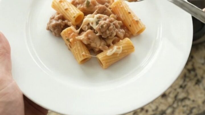 Creamy Boursin chicken rigatoni in a black slow cooker, topped with melted fontina and fresh herbs.